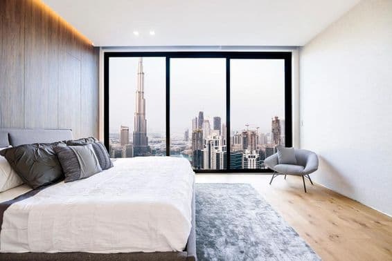Appartement à Dubaï, lit, chaise, vue panoramique, Burj Khalifa en arrière-plan.