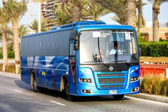 Autobus bleu de Dubaï avec des palmiers en arrière-plan.