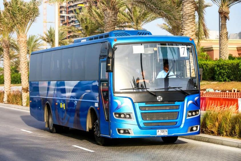Autobus bleu de Dubaï avec des palmiers en arrière-plan.
