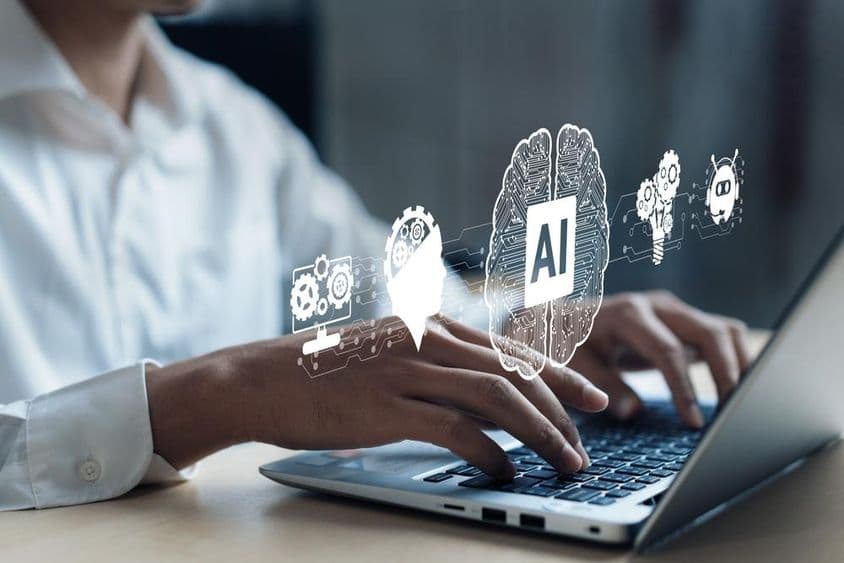 Projection sur un cahier montrant un cerveau d'IA et d'autres éléments. Une main humaine travaillant sur l'ordinateur.