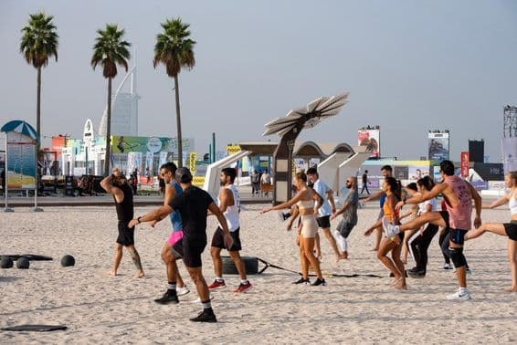 Un groupe de personnes s'exerçant sur une plage de sable lors du Défi Fitness de Dubaï.
