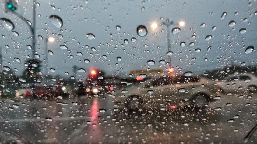 Voitures apparaissant floues à travers du verre couvert de pluie.