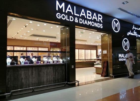 Un Émirati se tient devant la vitrine du magasin Malabar Gold & Diamonds.