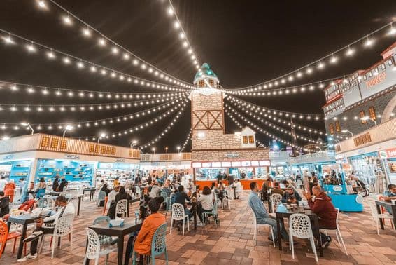 Global Village, touristes et locaux goûtant des spécialités culinaires à des tables.