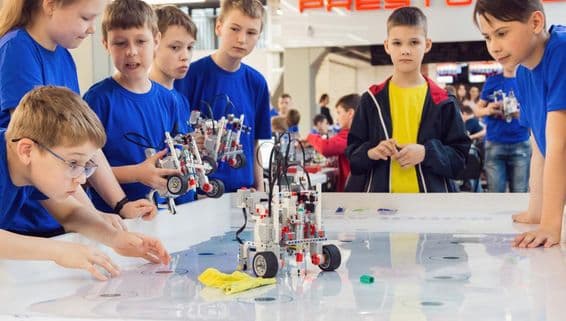 Des étudiants en chemises bleues construisant et programmant un robot.