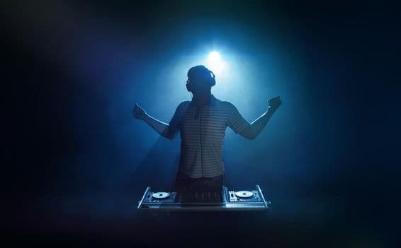 Une personne se tient derrière la cabine du DJ.