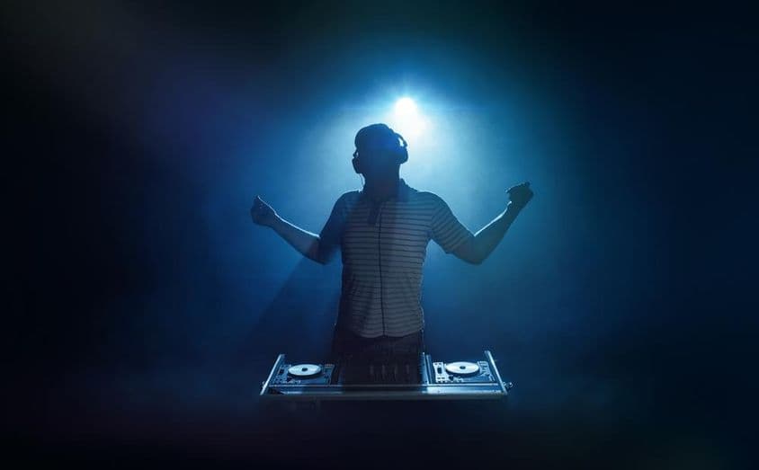 Une personne se tient derrière la cabine du DJ.