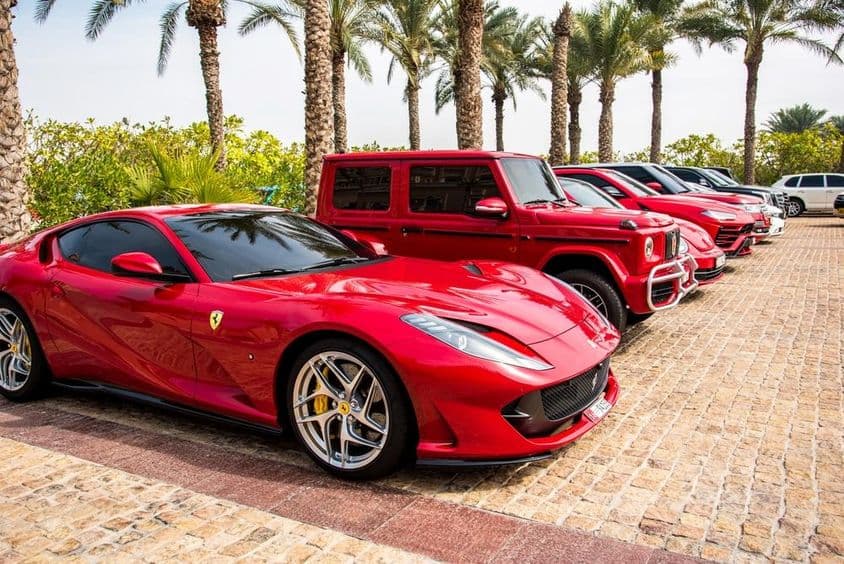 Voitures de luxe rouges alignées à Dubaï, avec Ferrari, Porsche, Mercedes.