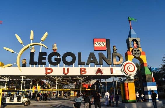 Entrée de LEGOLAND Dubai avec des personnes et une voiturette de golf devant.