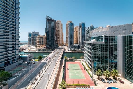 Un court de tennis à Dubaï avec des gratte-ciels et un hors-bord sur l'eau.