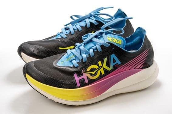 Une chaussure de sport Hoka avec un motif coloré, principalement noire, avec une semelle blanche.