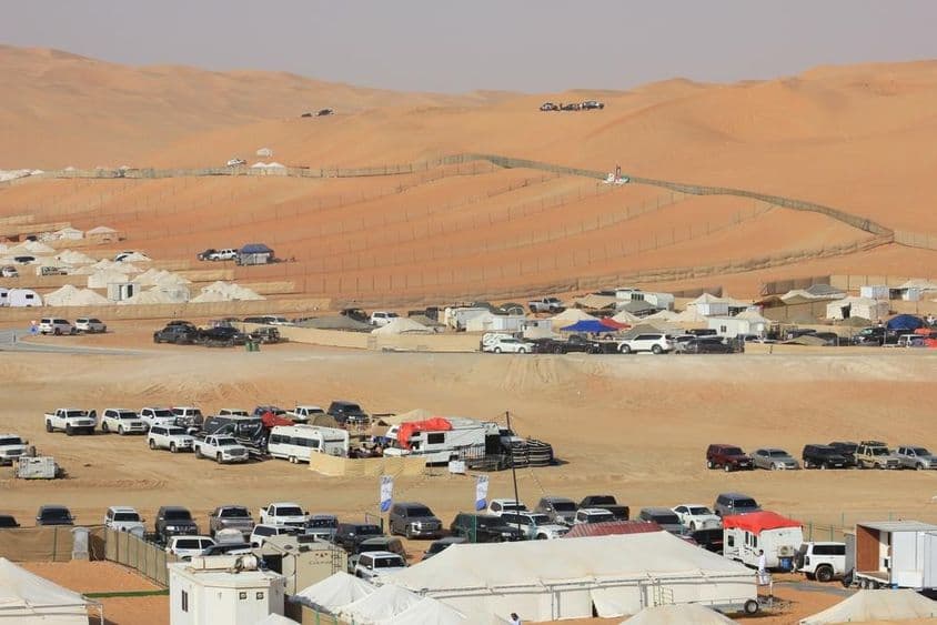 Paysage du Festival International de Liwa dans le désert avec voitures, camping-cars et tentes.