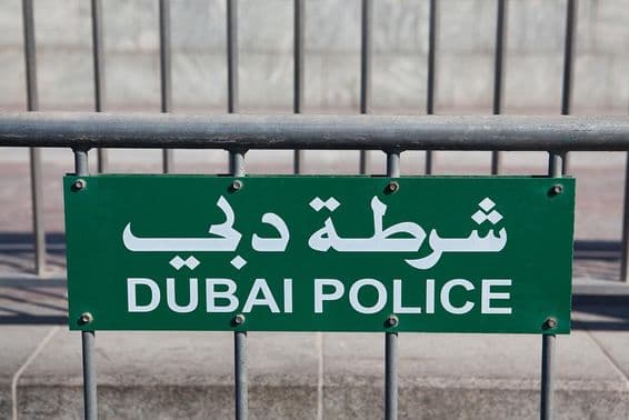 Panneau de la police de Dubaï visible sur une clôture.