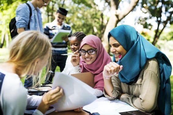 Étudiants à Dubaï écrivant des leçons et discutant en plein air.