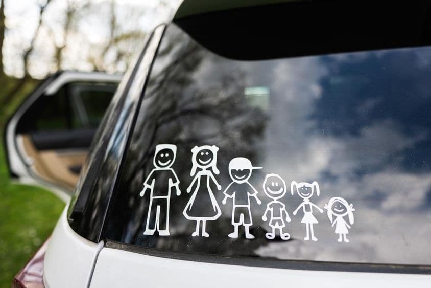 La vitre arrière d'une voiture affiche un autocollant de famille, incluant 2 adultes et 4 enfants.
