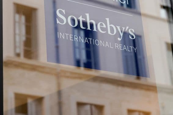 Enseigne de Sotheby's visible sur le devant d’un bâtiment, sur un panneau transparent.