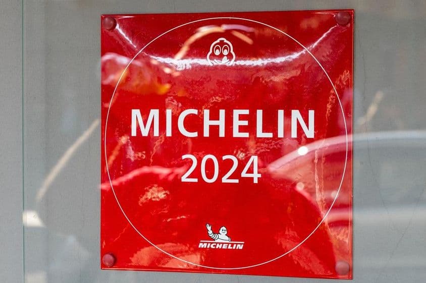 Une plaque du Guide Michelin 2024 vue sur un mur de restaurant.