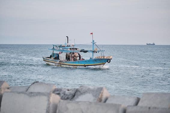 Un bateau de pêche usé en mer avec des personnes à bord.
