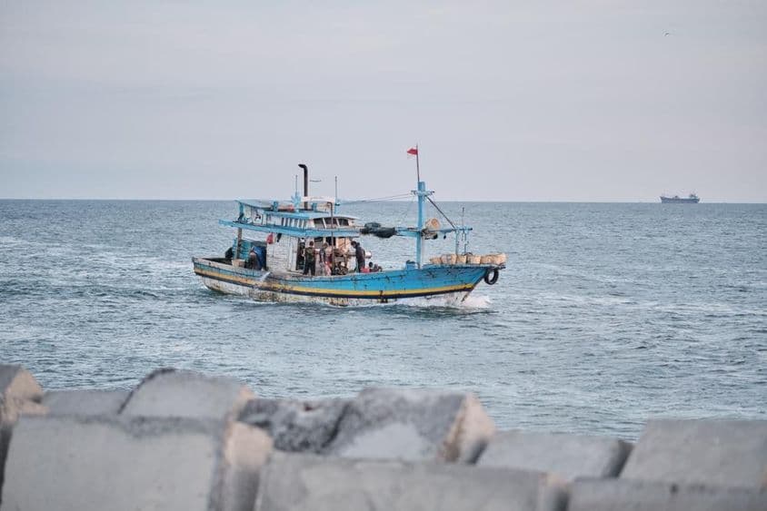 Un bateau de pêche usé en mer avec des personnes à bord.