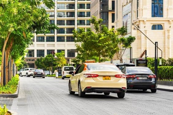 Voitures à Dubaï sur la route, un taxi au premier plan, maisons à l'arrière.