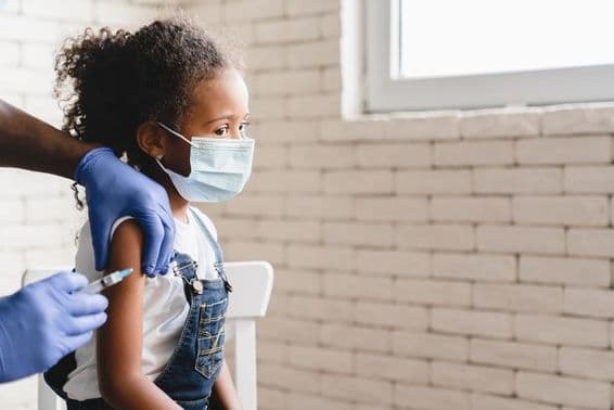 Fille recevant un vaccin avec un masque sur le visage.