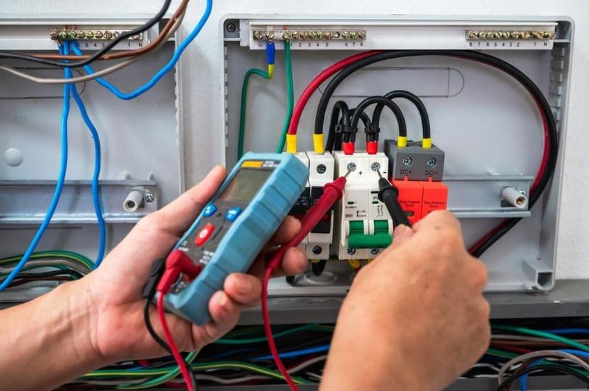 Électricien vérifiant une source d'alimentation avec un compteur.