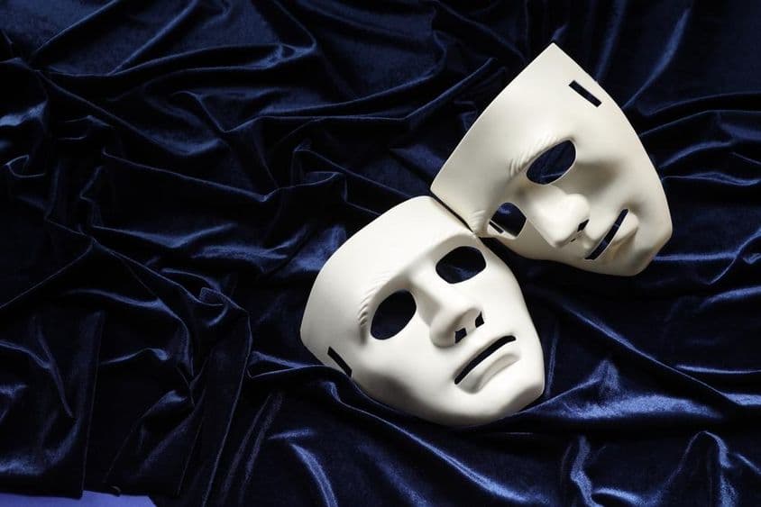 Théâtre, deux masques blancs sur du velours bleu.