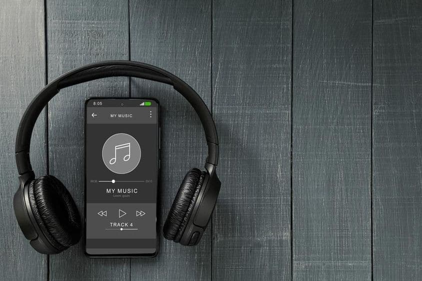 Lecture de musique sur un téléphone, avec des écouteurs à côté.