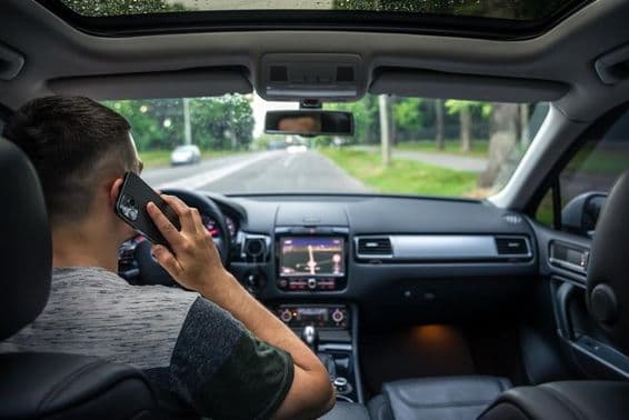 Jeune homme utilisant son téléphone en conduisant une voiture.