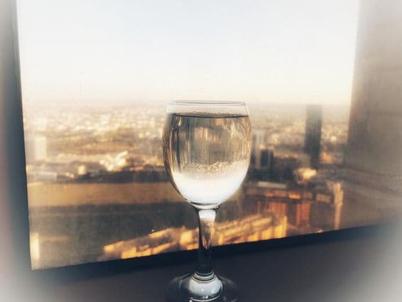 Un verre de vin sur une fenêtre avec vue sur la ville.