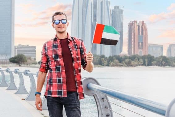 Jeune homme à la Marina de Dubaï tenant un drapeau des Émirats Arabes Unis.