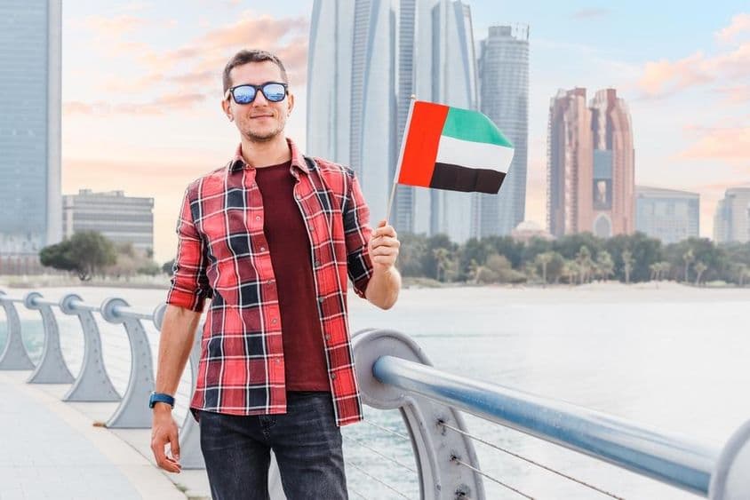 Jeune homme à la Marina de Dubaï tenant un drapeau des Émirats Arabes Unis.