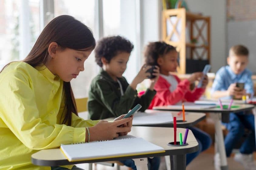Des enfants utilisant des téléphones dans une salle de classe.