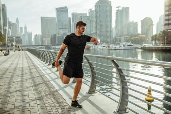Jeune homme s'étirant après une course le long du canal de Dubaï.