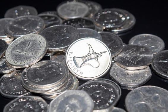 Une poignée de pièces de 1 dirham éparpillées.