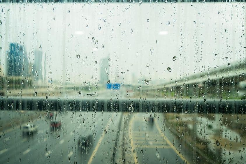 Gouttes de pluie sur une fenêtre avec quelques gratte-ciels flous en arrière-plan.