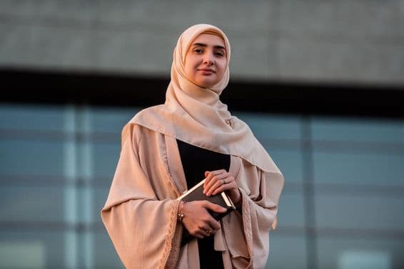 Étudiante à l'université de Dubaï tenant un livre.