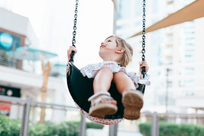 Une petite fille heureuse se balançant dans la cour du jardin d'enfants.