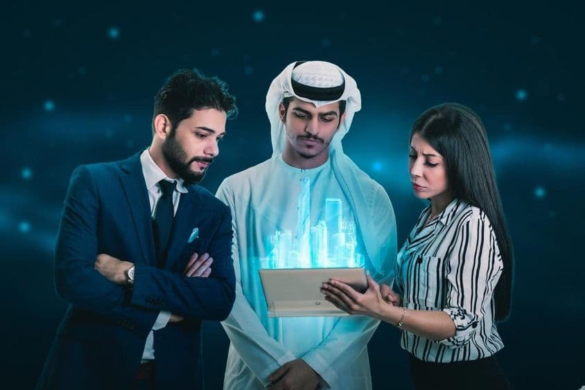 Deux hommes et une femme examinant un hologramme.