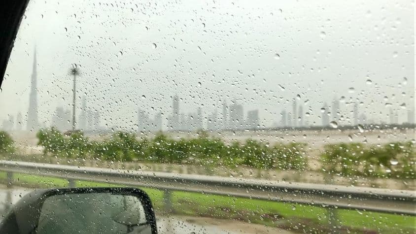 Gouttes de pluie glissant sur la vitre d'une voiture.