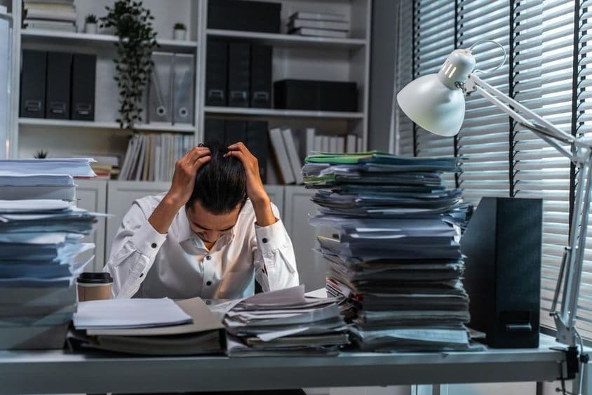 Travailleur de bureau tenant la tête en raison d'un travail accablant.