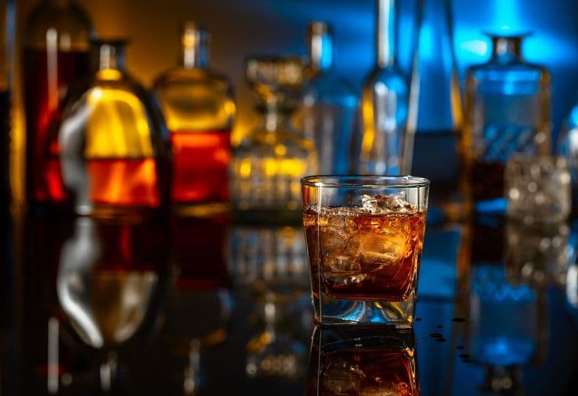 Whisky avec glaçons sur une table noire dans un bar.