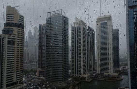 Gros plan d'une fenêtre mouillée montrant la ligne d'horizon commerciale moderne de Dubaï.