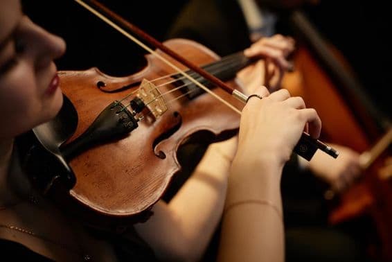 Femme musicienne d'orchestre jouant du violon avec un archet lors d'un concert sur scène.