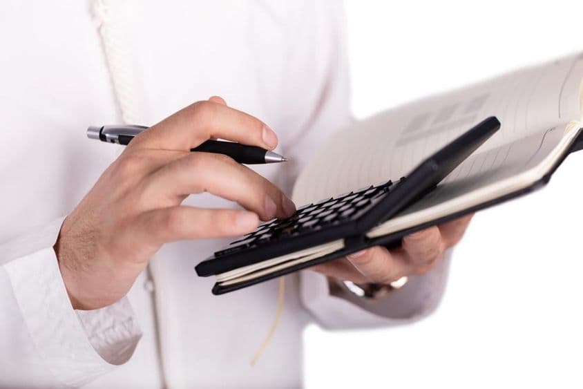 Homme d'affaires arabe tenant une calculatrice.