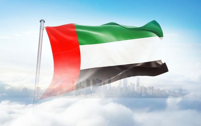 Drapeau des EAU flottant dans les nuages, gratte-ciels en arrière-plan.