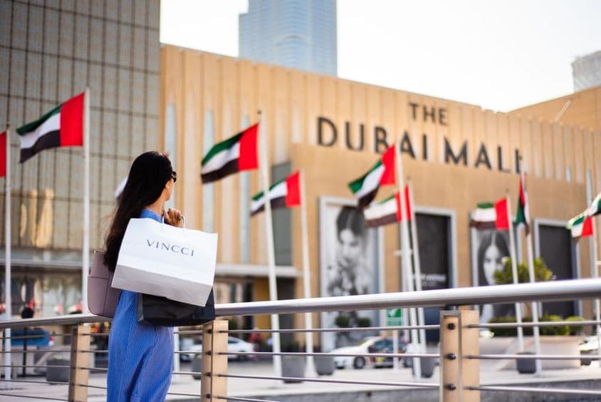 Femme arabe avec des sacs de shopping devant un centre commercial à Dubaï.