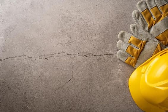 Temps de pause, casque jaune et gants de travail posés sur une surface en béton fissurée.
