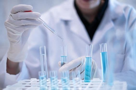 Scientifique pipetant un liquide bleu dans un tube à essai dans un laboratoire.