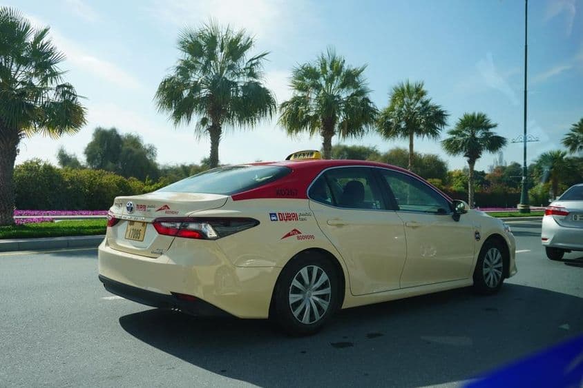 Taxi de Dubaï avec toit rouge roulant sur la route.